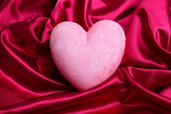 Cuore rosso decorativo, su sfondo tessuto colore — Foto Stock