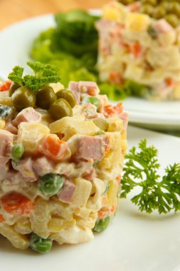 geleneksel Rus salatası olivier, tahta masada gri arka plan üzerinde renkli peçete üzerinde