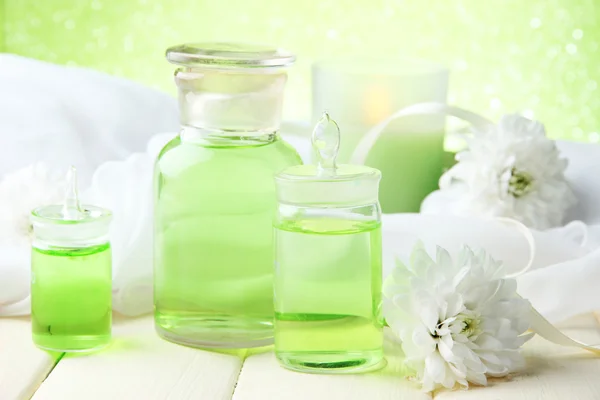 Bottiglie di vetro con essenza di colore, su tavolo di legno, su sfondo verde — Foto Stock