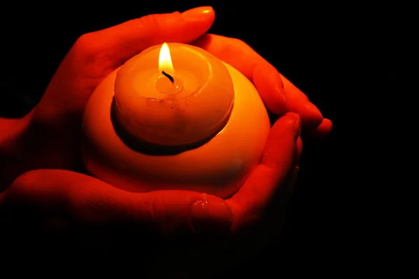 Burning candle in hands isolated on black — Stock Photo, Image