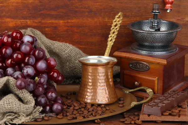 Кофемолка, турок и кофейных зерен на золотом подносе на деревянном фоне — стоковое фото