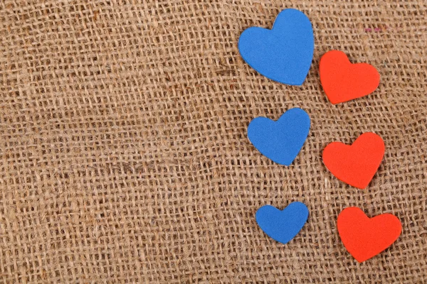 Hearts made of felt on sacking background — Stock Photo, Image