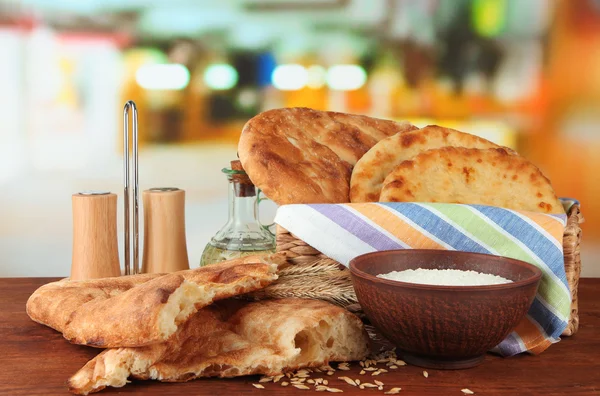Pane pita in cesto con spezie e farina sul tavolo su sfondo brillante — Foto Stock