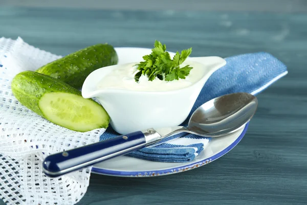 Cucumber yogurt in sauceboat, on color napkin, oncolor wooden background — Stock Photo, Image