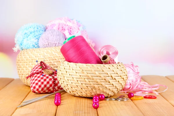 Handicraft supplies in basket on wooden table on bright background — Stock Photo, Image