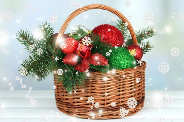 Christmas decorations in basket and spruce branches on table on bright background — Stock Photo, Image