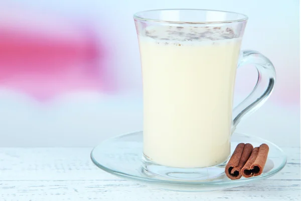 Cup of eggnog with cinnamon on table on bright background — Stock Photo, Image