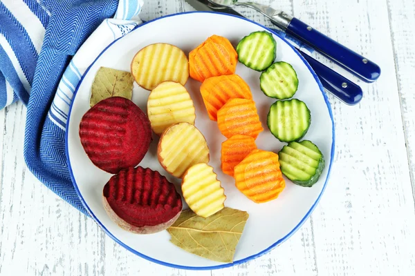 Beautiful sliced vegetables, on plate, on wooden background — Stock Photo, Image