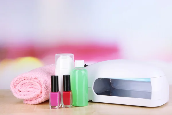 Lampy dla paznokci i akcesoria do manicure na stole na jasnym tle — Zdjęcie stockowe