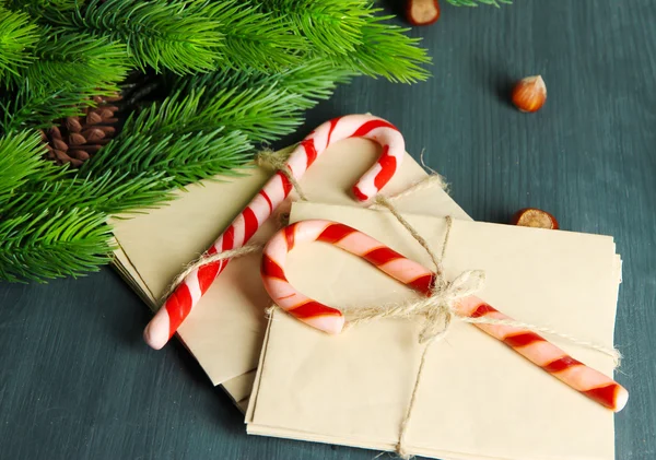 Bastoncini di zucchero natalizio e lettere per Babbo Natale, su sfondo di legno a colori — Foto Stock