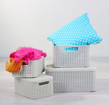 Plastic baskets with things in floor on room background clipart