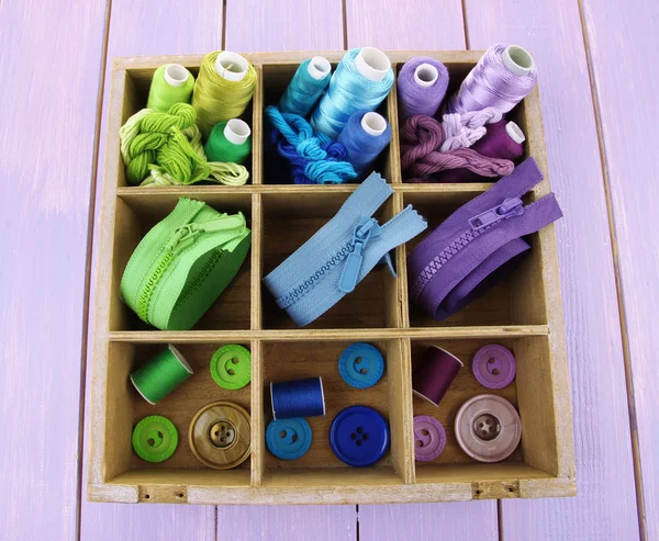 Multicolored skeins of thread with fasteners and buttons in box closeup — Stock Photo, Image
