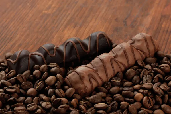 Deliciosas barras de chocolate con granos de café en la mesa de madera de cerca — Zdjęcie stockowe