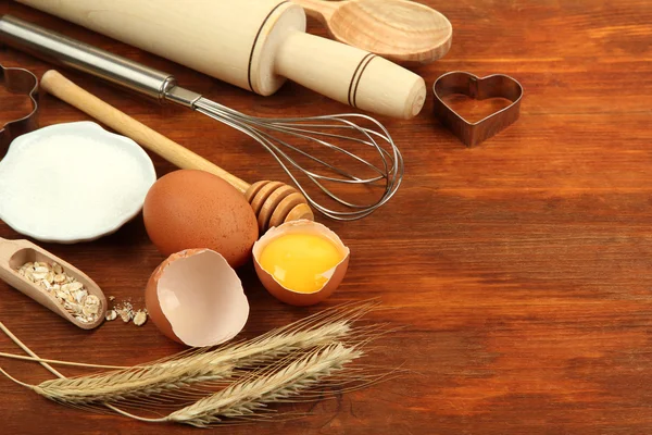 Vaření koncepce. základní pečící ingredience a kuchyňské nástroje na dřevěný stůl — Stock fotografie