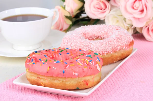 Süße Donuts mit einer Tasse Tee auf dem Tisch vor hellem Hintergrund — Stockfoto