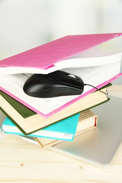 Computer mouse on books and notebook on wooden table on room background — Stock Photo, Image