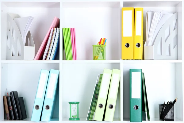 Prateleiras de escritório branco com pastas e artigos de papelaria diferentes, close-up — Fotografia de Stock