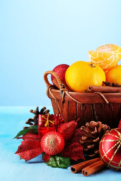 Christmas tangerines in basket on blue background — Stock Photo, Image