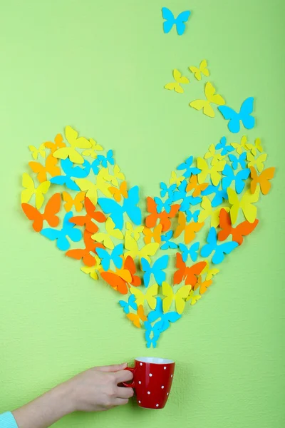 Paper butterflies fly out of cup on green wall background — Stock Photo, Image