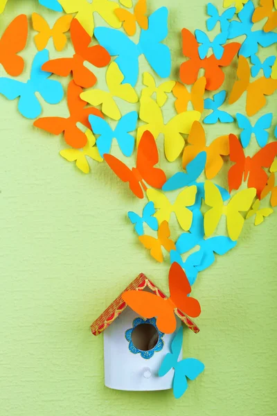 Farfalle di carta volare fuori scatola di nidificazione su sfondo muro verde — Foto Stock