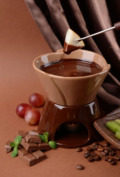 Chocolade fondue met fruit, op bruine achtergrond — Stockfoto