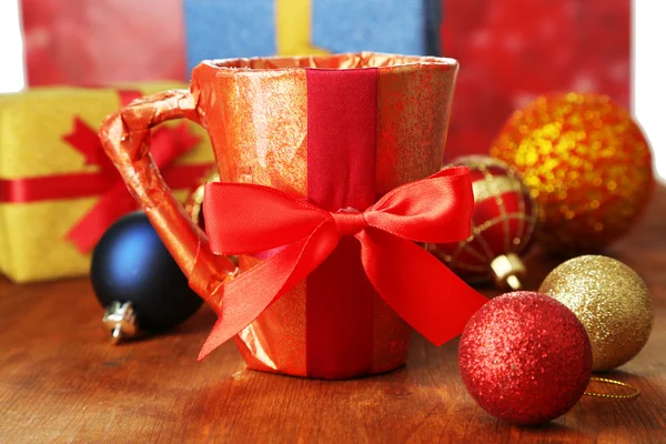 Copa envasada en papel de regalo con regalos en mesa de madera sobre fondo brillante —  Fotos de Stock