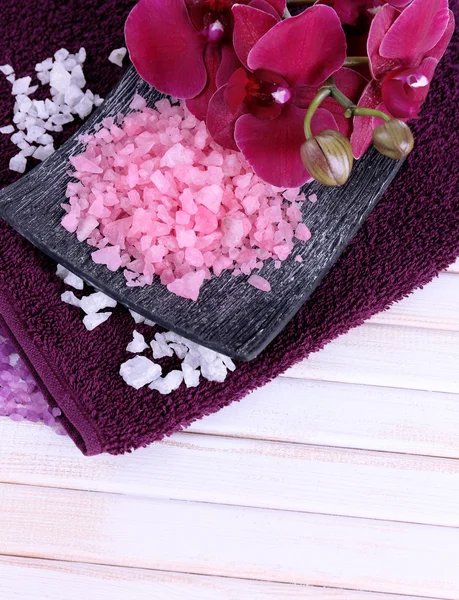 Bodegón con hermosa flor de orquídea y cucharas de madera con sal marina, sobre fondo de madera de color —  Fotos de Stock