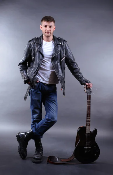 暗い色の背景上のギターを持つ若い音楽家 — ストック写真