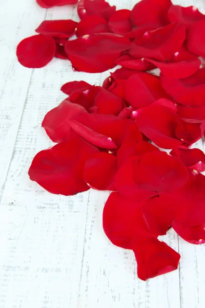 Piękne płatki czerwonych róż na drewniany stół szczegół — Zdjęcie stockowe