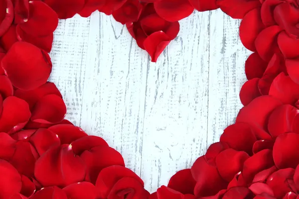 Schönes Herz aus roten Rosenblättern auf Holztisch in Großaufnahme — Stockfoto