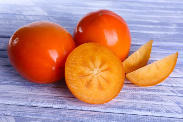 Rijpe persimmons op houten ondergrond — Stockfoto