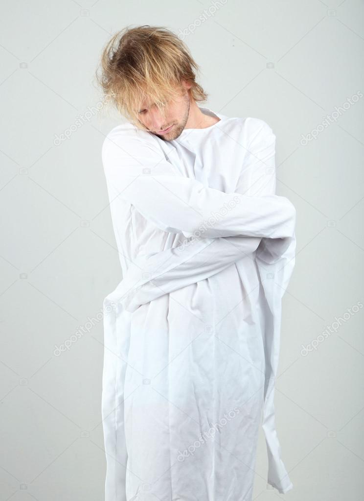 Mentally ill man in strait-jacket on gray background