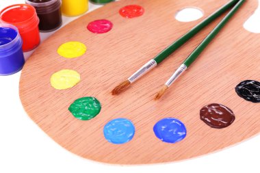 Wooden art palette with paint and brushes close-up clipart