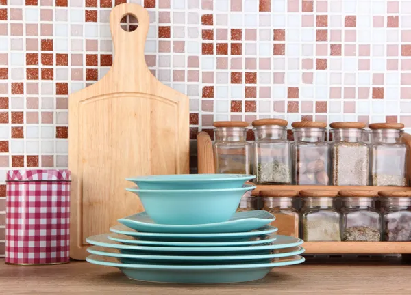 Plates in kitchen on table on mosaic tiles background — Stock Photo, Image