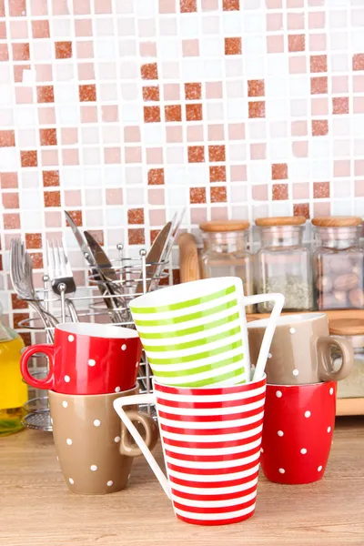 Cups in kitchen on table on mosaic tiles background — Stock Photo, Image