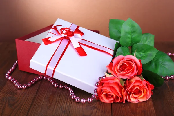 Beautiful gift box with flowers on table on brown background — Stock Photo, Image