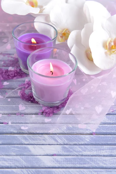 Hermosas velas de colores y flores de orquídea, sobre fondo de madera de color —  Fotos de Stock
