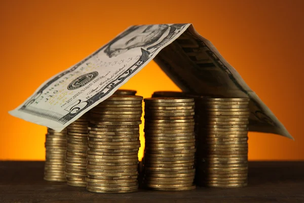 Coins house on table on brown background — Stock Photo, Image