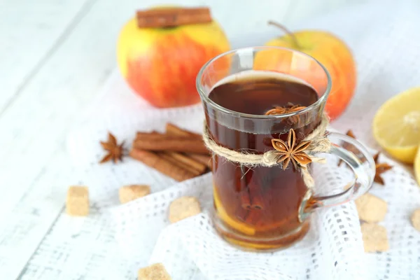 Bevanda calda in tazza di vetro con frutta e spezie, su fondo di legno — Foto Stock