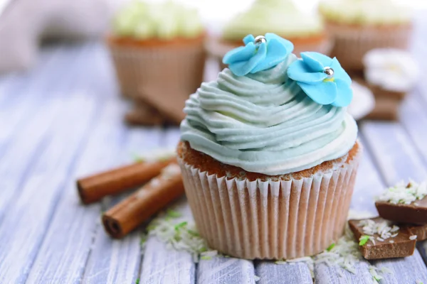 Cupcakes saborosos com creme de manteiga, na cor de fundo de madeira — Fotografia de Stock