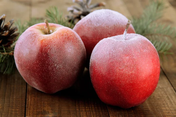 Červená matné jablka s jedle větev a hrboly na dřevěné pozadí — Stock fotografie