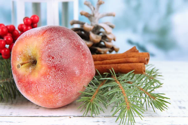 Новорічна композиція з червоним зимовим яблуком на столі крупним планом — стокове фото