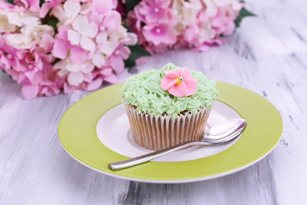 Smakelijke cupcake met boter room, op de plaat, op een houten achtergrond kleur — Stockfoto