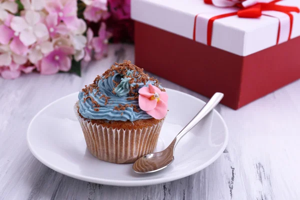 Tasty cupcake with butter cream, on plate, on color wooden background — Stock Photo, Image