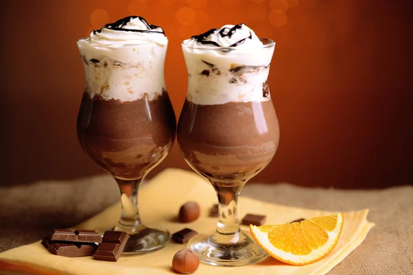 Вкусный десерт с шоколадом, сливками и апельсиновым соусом, на деревянном столе, на фоне огней — стоковое фото