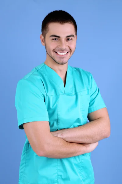 Mladý muž lékař na modrém pozadí — Stock fotografie