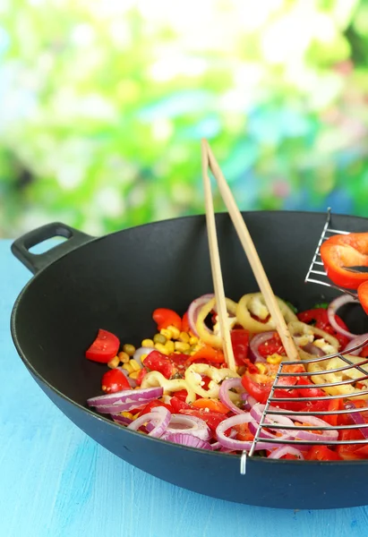 Vegetables in wok on wooden table on natural background — Stock Photo, Image