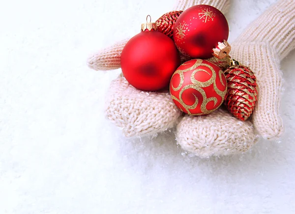 Vrouwelijke handen in wanten kerstboom ballen, op een achtergrond met kleur — Stockfoto