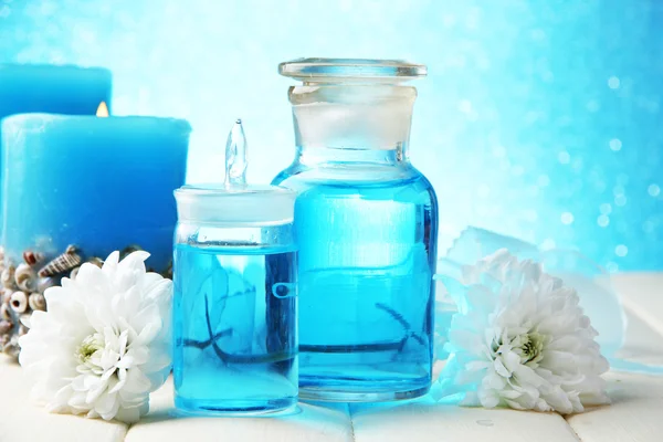 Стеклянные бутылки с цветовой сущностью, на деревянном столе, на синем фоне — стоковое фото