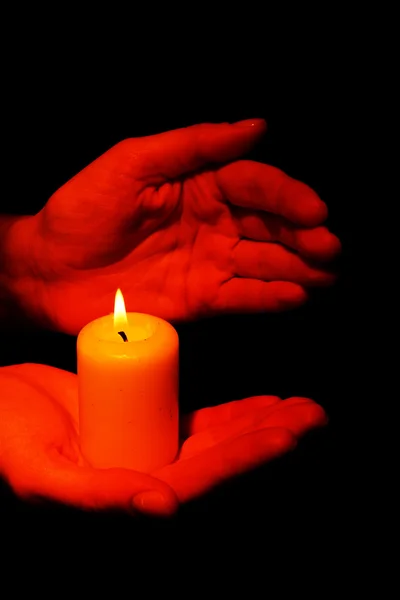 Brennende Kerze in den Händen isoliert auf schwarz — Stockfoto